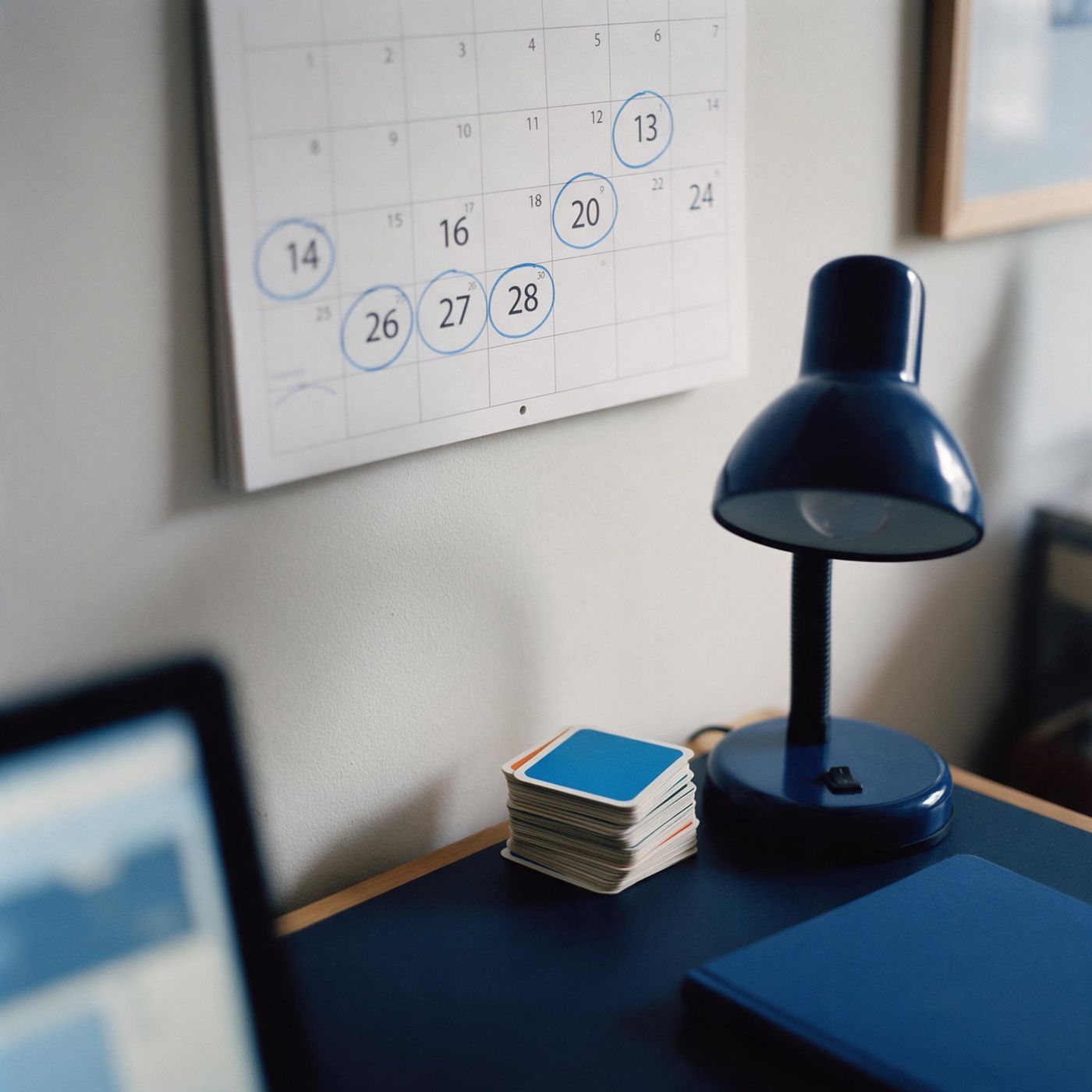 A wall calendar with days circled in blue at widening gaps above a desk with flashcards